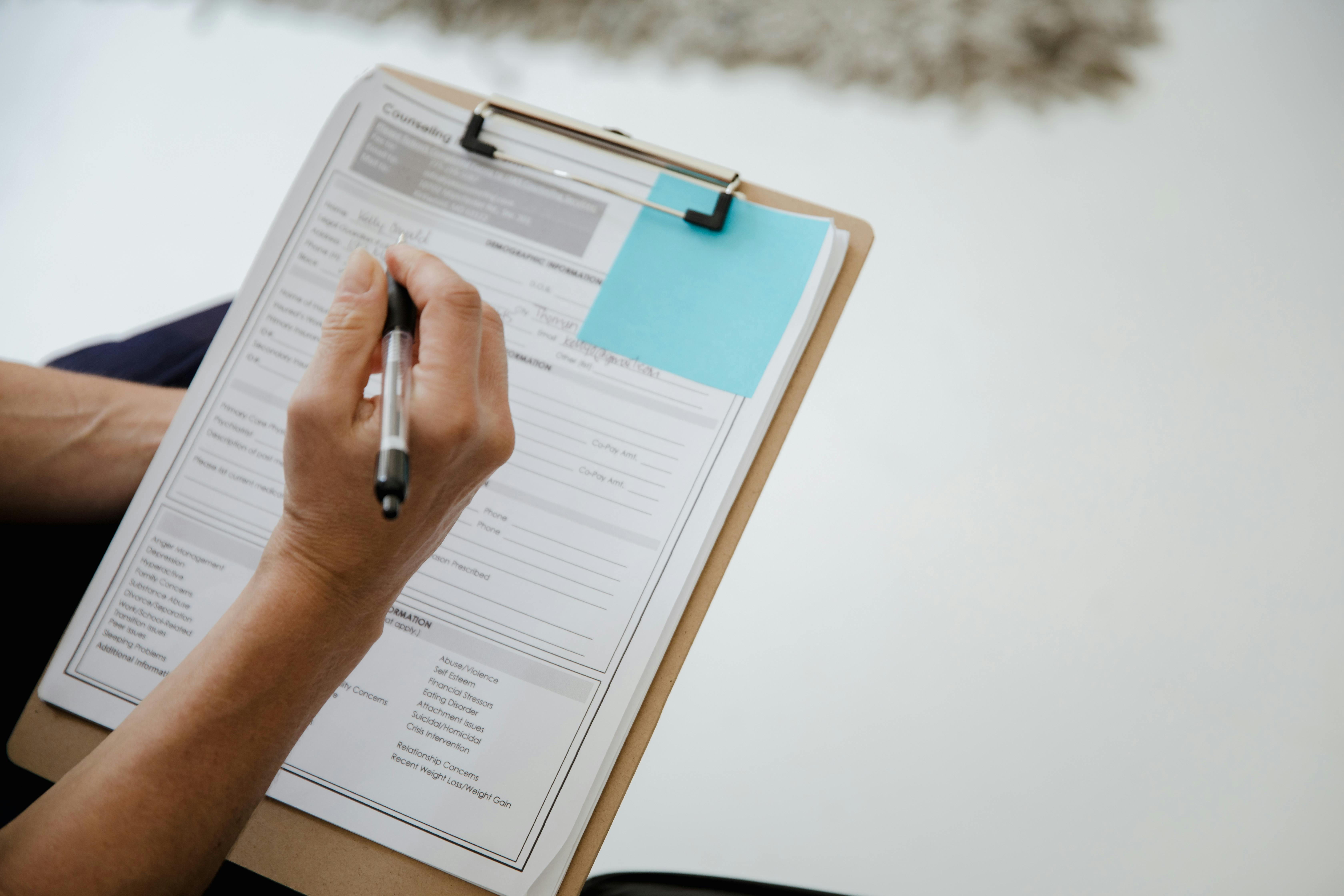 Person filling out a form on a clipboard
