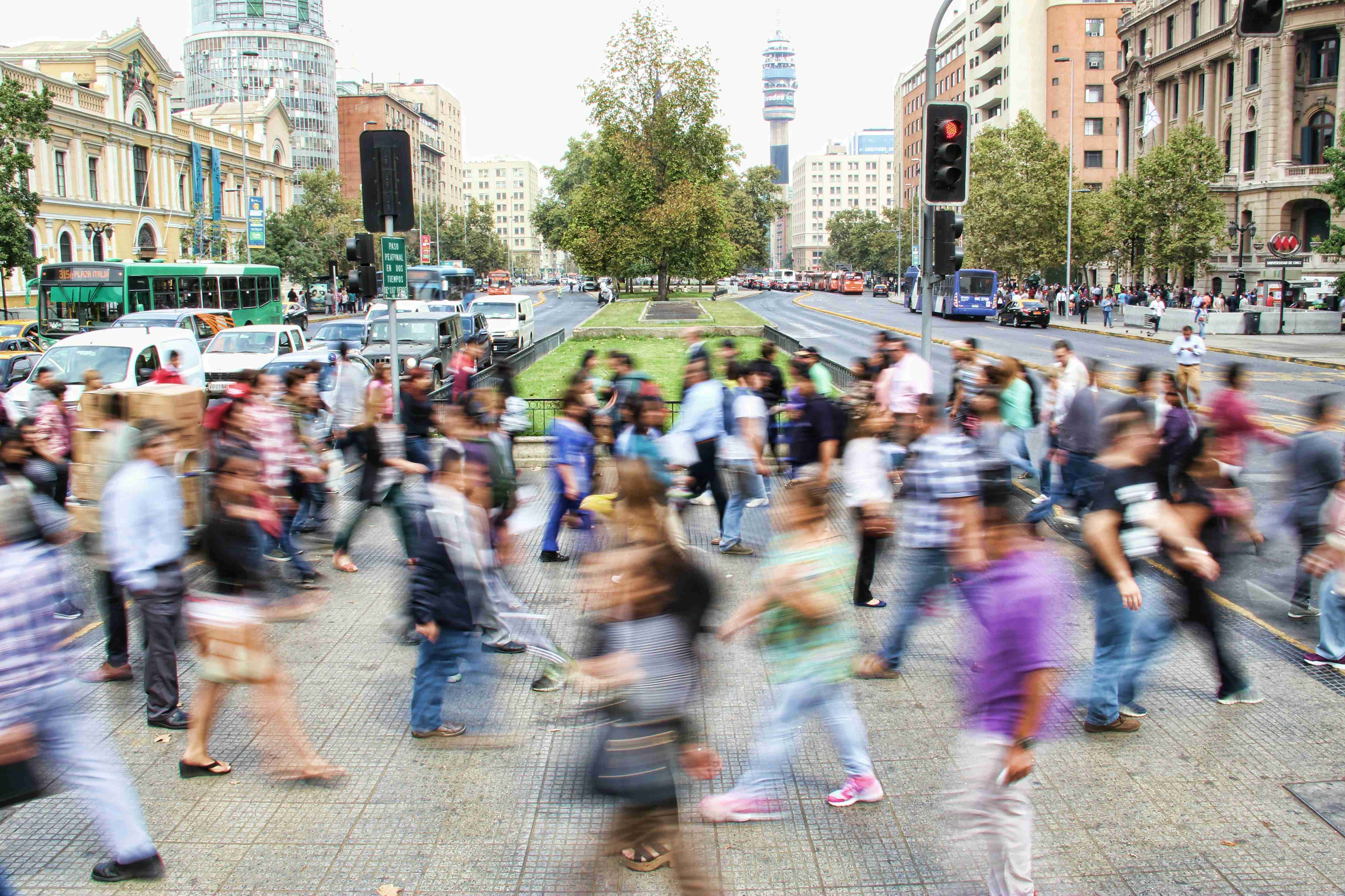 Crowd of people crossing a busy city street with blurred motion.