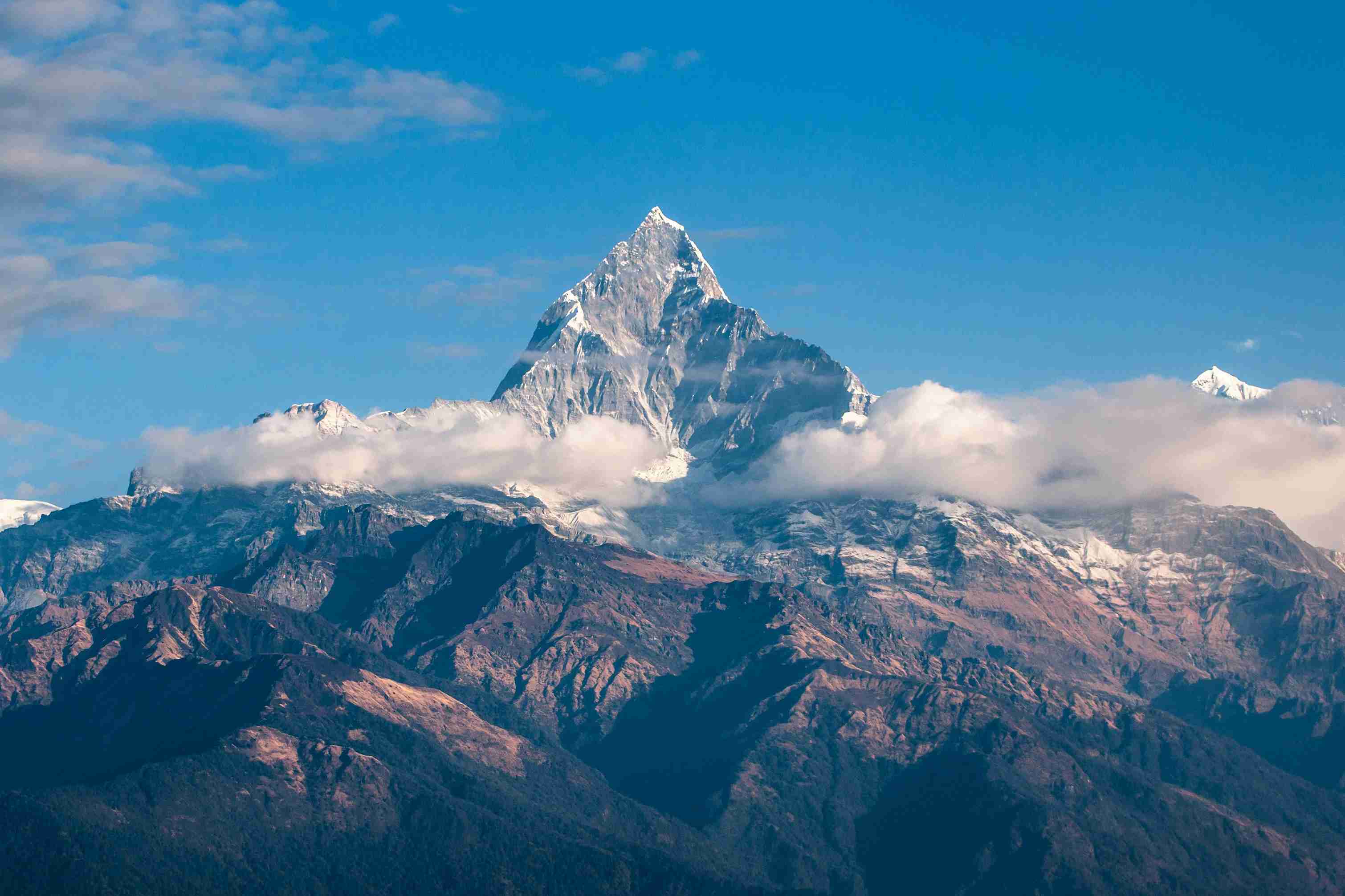 Mountain landscape with a prominent peak rising above cloud-covered ridges